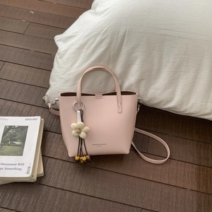 Pink matte leather bucket bag with silver hardware and a beige woven flower charm
