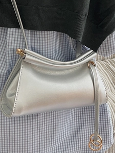 Minimalist silver dumpling crossbody bag with metallic sheen and golden ring charm
