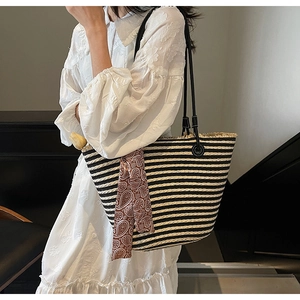 Detail of hand-woven straw tote with black and white stripes and a brown paisley scarf