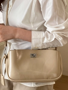 Minimalist beige baguette crossbody bag with silver lock clasp and glossy finish