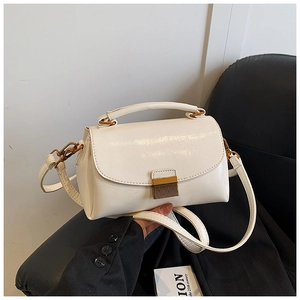 Détail du petit sac blanc vintage avec boucle dorée posé sur un siège en cuir noir