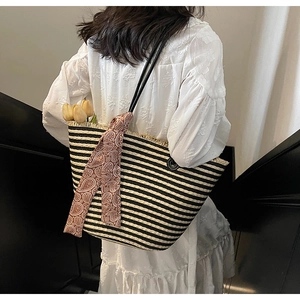 Détail du cabas en paille tissée à rayures noires avec accent de foulard en soie marron