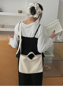 Model wearing a cream minimalist tote bag with adjustable shoulder strap and top handle