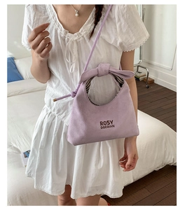 Detail of lavender matte handbag featuring a stylish bow handle and brand lettering