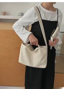 Detail view of cream leather shoulder bag with decorative stitching on soft textured surface