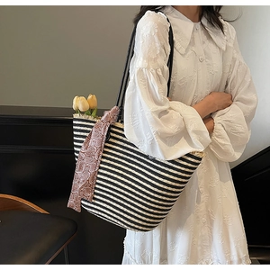 Detail of hand-woven striped straw tote bag with brown paisley silk scarf and tulip decor