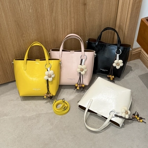 Detail showing bucket bags in four colors with floral charms and wooden tassels