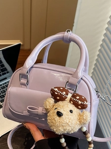 Minimalist light purple bow handbag with plush bear charm in a lifestyle casual setting
