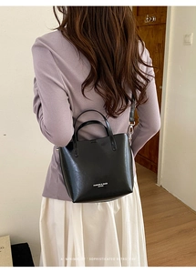 Detailed back view of a black leather bucket bag with top handles and a shoulder strap