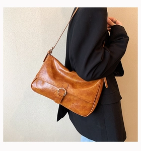 Detail of caramel faux leather shoulder bag with vintage metal buckle and adjustable strap