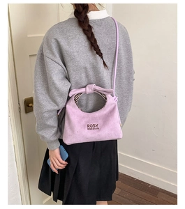 Light purple faux suede bucket bag featuring bow handles and a striped lining