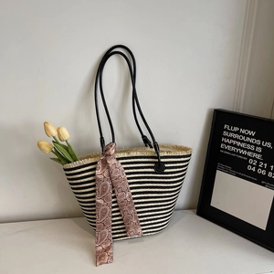 Detail of hand-woven striped straw tote with fringe edges and paisley silk scarf