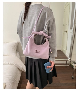 Detail of purple suede hobo bag with logo print and knotted handle on shoulder