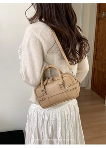 Sac Boston beige avec bandoulière présenté dans un décor de style de vie minimaliste