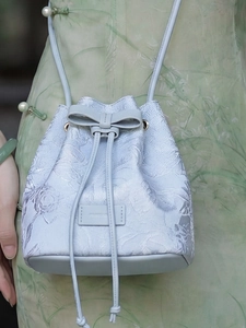 Sac seau bleu clair brodé de fleurs avec détail nœud porté par un mannequin en qipao
