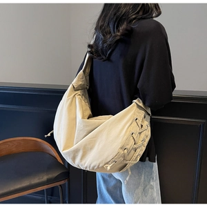 Détail d'un sac bandoulière croissant avec cordons décoratifs et texture en toile beige