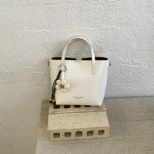 White bucket tote bag featuring a floral charm and Fashion & Bags leather lettering