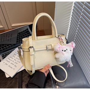 Close-up of cream square crossbody bag with silver buckle and cute plush bear charm