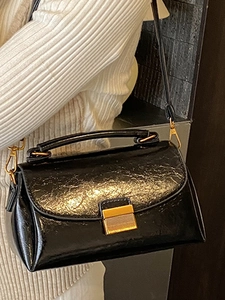 Sac à main rétro en cuir noir avec fermoir doré porté à l'épaule par le mannequin