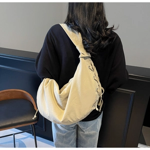 Vue détaillée du sac besace en toile beige avec cordons élégants sur la bandoulière