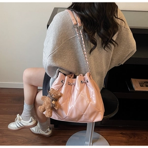 Detail view of pink quilted patent leather bucket bag with plush bear charm and chain strap