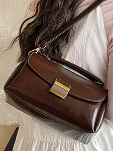 Petit sac carré marron rétro avec finition brillante et boucle dorée porté à l'épaule