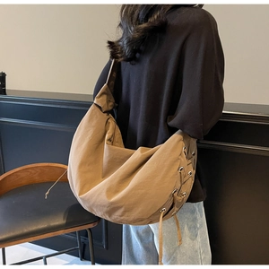 Sac croissant en nylon marron porté par un mannequin avec bandoulière nouée et cordons latéraux
