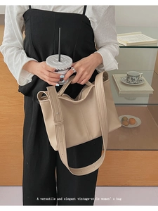 Detail of a vintage beige leather tote bag with wide shoulder straps and zipper closure