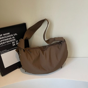 Vue détaillée du sac dumpling en nylon marron avec œillets métalliques et détails de cordon