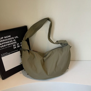 Détail du sac croissant vert olive montrant la texture nylon souple et la bandoulière