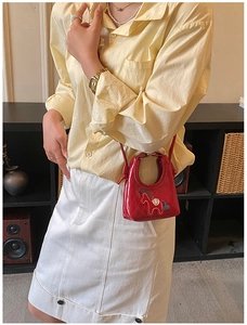 Gros plan d'un mini sac en cuir verni rouge matelassé avec une broderie de cheval en 3D