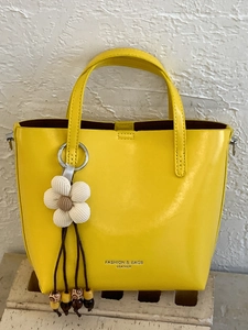 Chic yellow leather bucket bag with white flower charm and elegant top handle for women