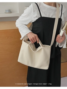 Detail of elegant beige leather handbag with center stitching shown in a minimalist room