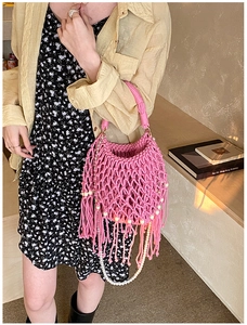 Dettaglio della borsa a tracolla intrecciata rosa con frange e catena di perle decorata