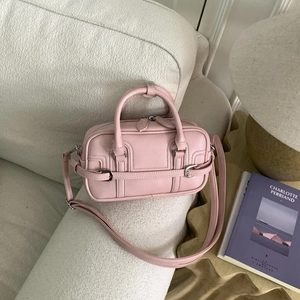 Sac bowling en cuir rose avec boucles argentées sur canapé en laine blanche