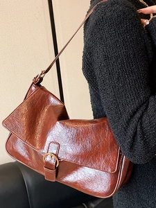 Brown faux leather shoulder bag with gold circular buckle and glossy finish for women