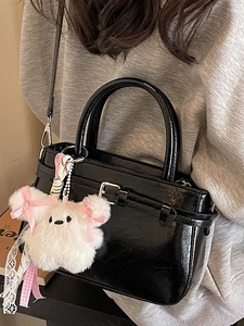 Chic glossy black patent leather square crossbody bag with a plush white charm pendant