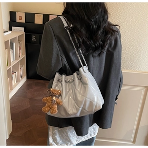 Quilted bucket bag in light grey-blue with silver chain and a plush bear charm detail