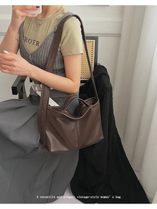 Detail of deep brown vintage leather tote bag with dual handles and long shoulder straps