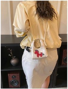 Détail du mini sac carré matelassé crème avec patch poney porté en bandoulière par le mannequin
