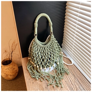 Dettaglio della borsa macramè verde salvia con nappe intrecciate e perline di legno