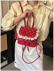 Détail d'un mini sac à dos rouge à pois avec bordure en dentelle et nœud décoratif