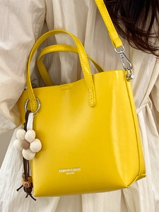 Vibrant yellow faux leather bucket bag with white flower charm and silver crossbody strap