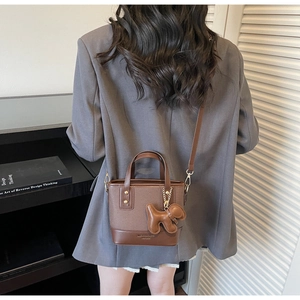 Détail d'un mini sac cabas marron avec un pendentif chien mignon et une bandoulière fine