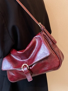 Deep red patent leather crossbody bag with silver buckle flap closure and shoulder strap
