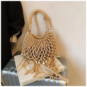 Dettaglio della borsa a tracolla intrecciata beige con nappe a frangia e perle