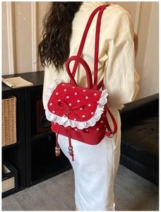 Détails d'un sac à dos rouge à pois avec bordure en dentelle, nœud et pendentif en cœur