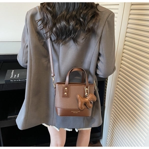 Détail du sac seau marron vintage avec logo de marque et pendentif chien en cuir