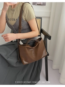 Close-up of vintage brown leather handbag with vertical stitching and adjustable shoulder strap