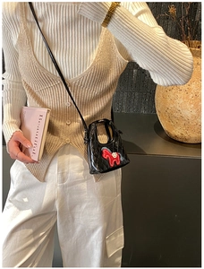 Détail d'un mini sac bandoulière en cuir verni noir matelassé avec écusson de cheval